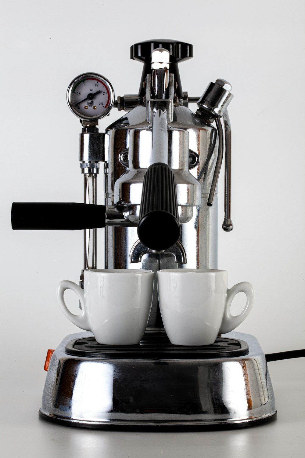 white ceramic teacup on stainless steel espresso machine