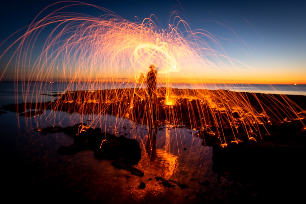 silhouette of person standing on rock formation during sunset