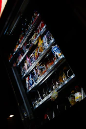 A staff member restocking snacks and drinks in a vending machine during business hours.