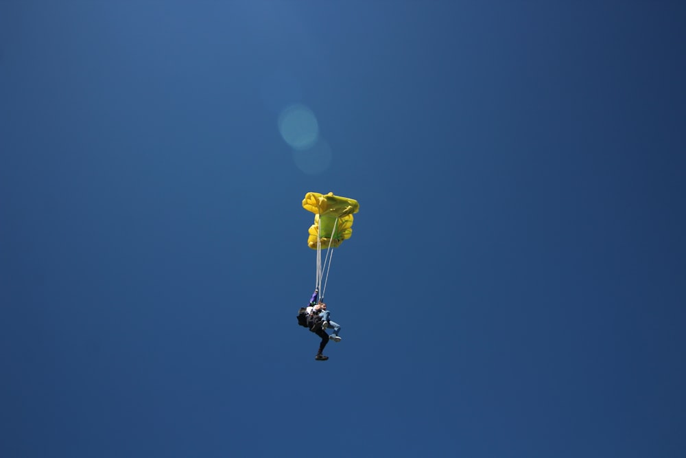 person in black jacket and black pants with yellow balloon in mid air