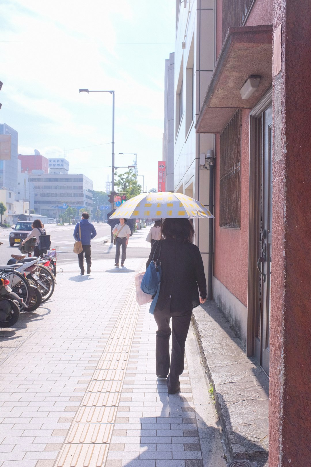 woman in black jacket holding umbrella walking on sidewalk during daytime