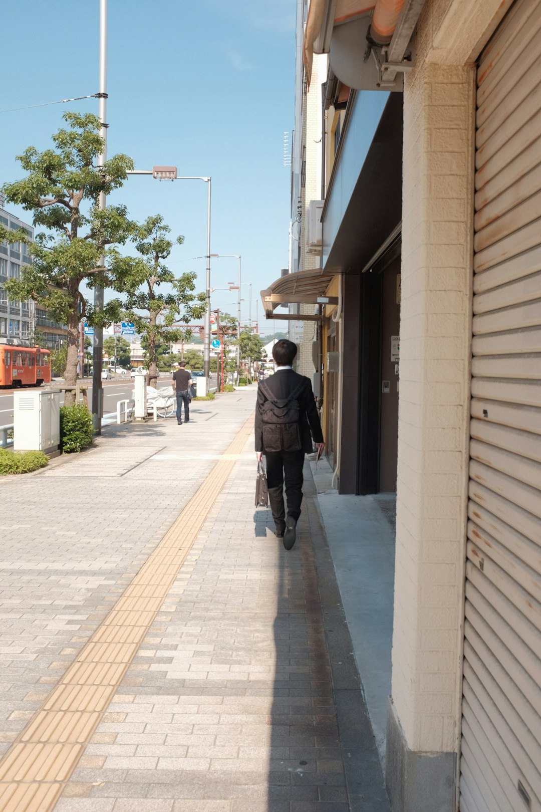 man in black jacket walking on sidewalk during daytime