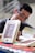 A person is sitting at a table, engaged with a book. The focus is on several books with a cover design featuring abstract art and the title 'Repassado'. The person appears to be reading, creating a scholarly or contemplative atmosphere.
