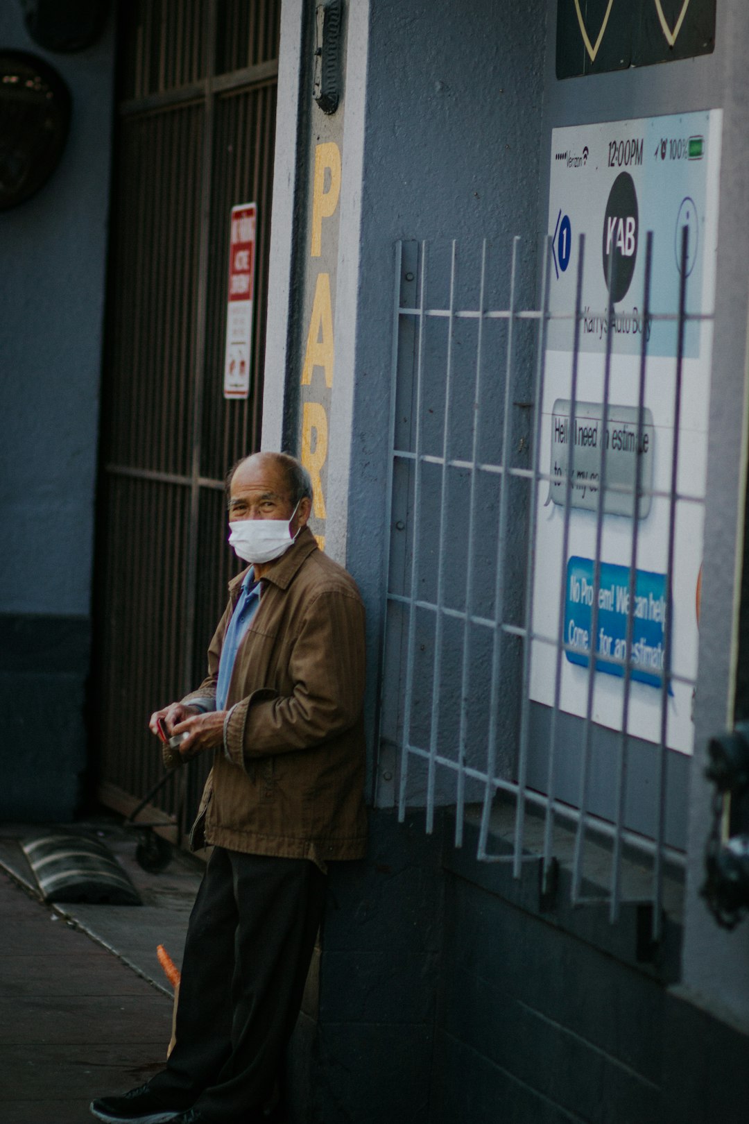 man in brown coat standing near white building during daytime