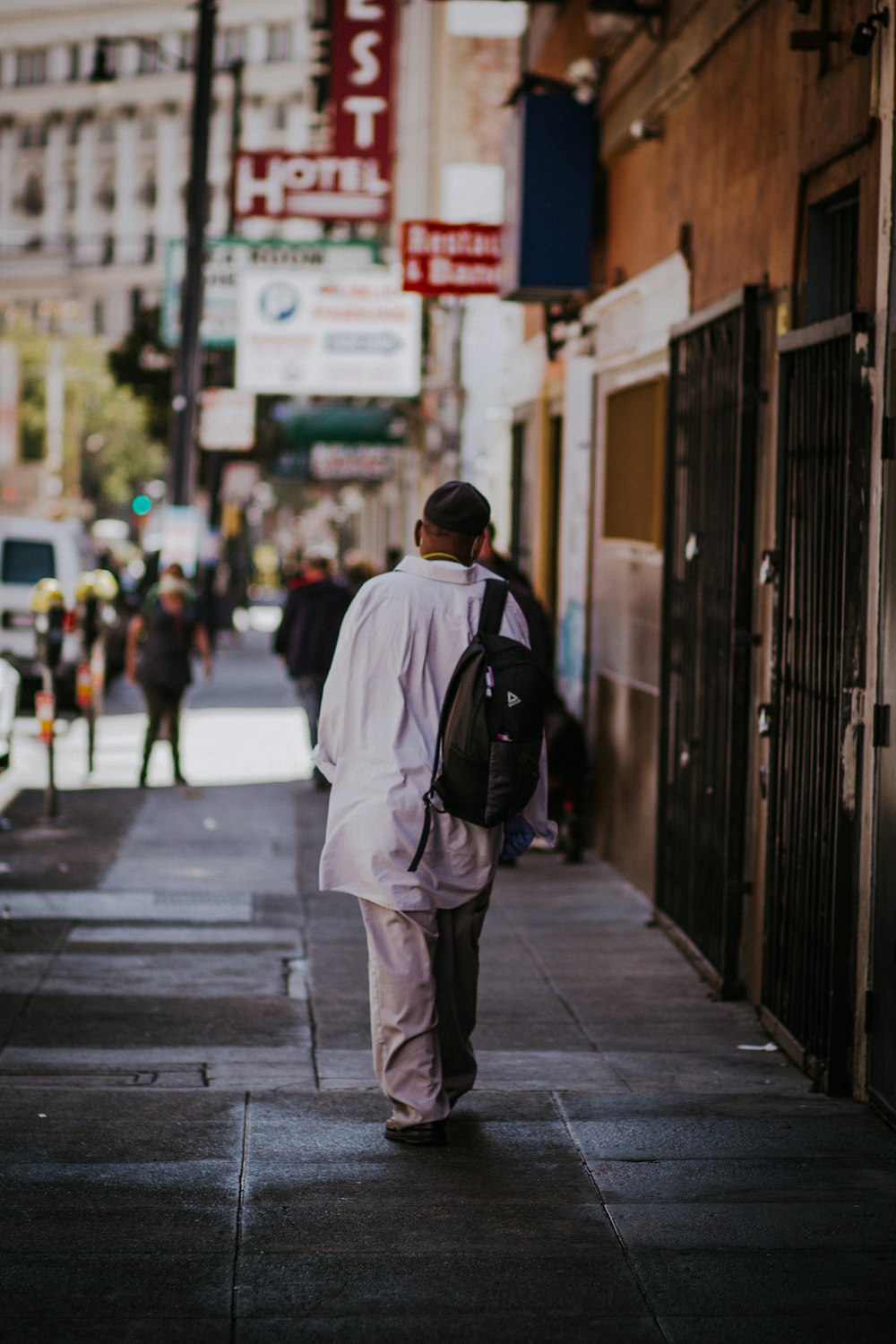 man in white jacket walking on sidewalk during daytime