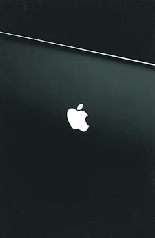 silver macbook on black table