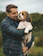 man in black leather jacket holding white and brown long coated small dog
