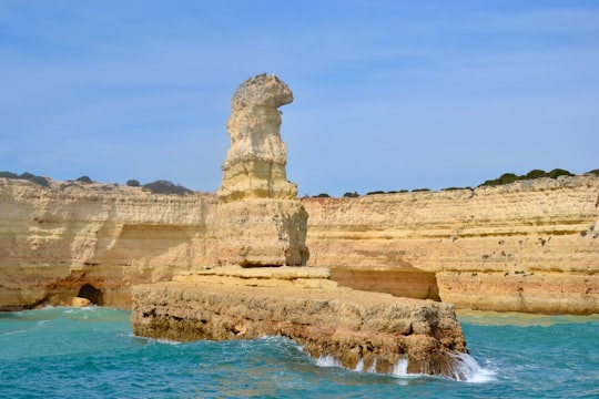 brown rock formation on blue sea under blue sky during daytime in Algarve Portugal