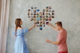 An intimate shot of hands arranging photographs on a minimalist gallery wall.