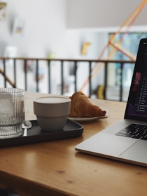A cozy workspace with a laptop and a cup of coffee on a wooden table.