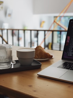 A cozy workspace with a laptop, coffee cup, and shopping packages on a wooden table