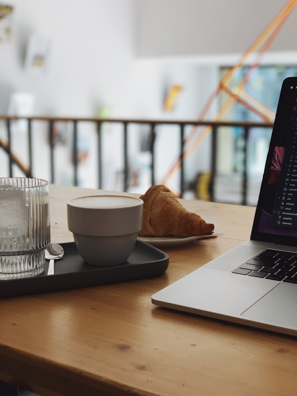 A cozy workspace with pastel green and beige tones, featuring eco-friendly tea packaging and a wooden table with a steaming cup of tea.