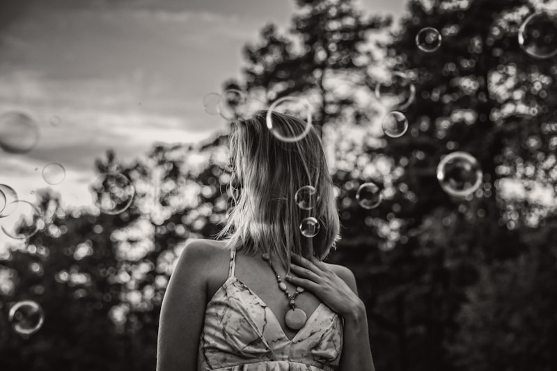 grayscale photo of woman blowing bubbles