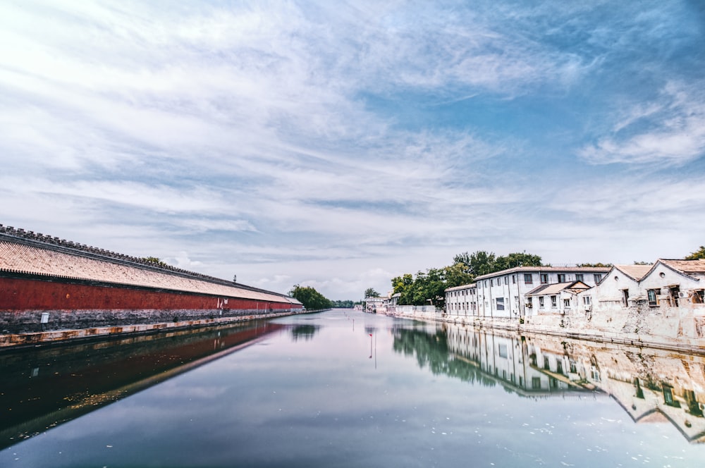 white and red concrete building near body of water under cloudy sky during daytime