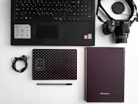 A flat lay of premium branded office accessories including notebooks, tech gadgets, and custom stationery items.