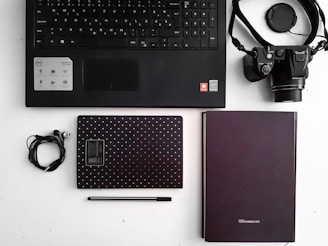 Flat lay of office supplies including pens, paper, and a laptop on a desk.
