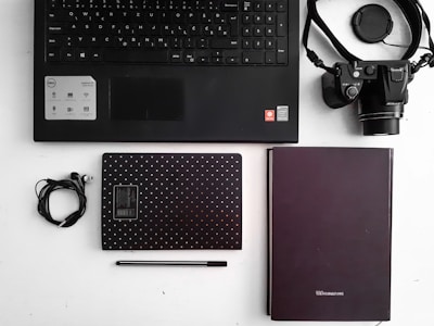 Flat lay of office supplies including pens, paper, and a laptop on a desk.