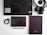 A flat lay of office and tech items arranged on a white surface. Includes a black keyboard, a camera with a strap, two notebooks—one black with white dots and the other plain, a pair of earphones, and a black pen. The layout is organized and minimalist.