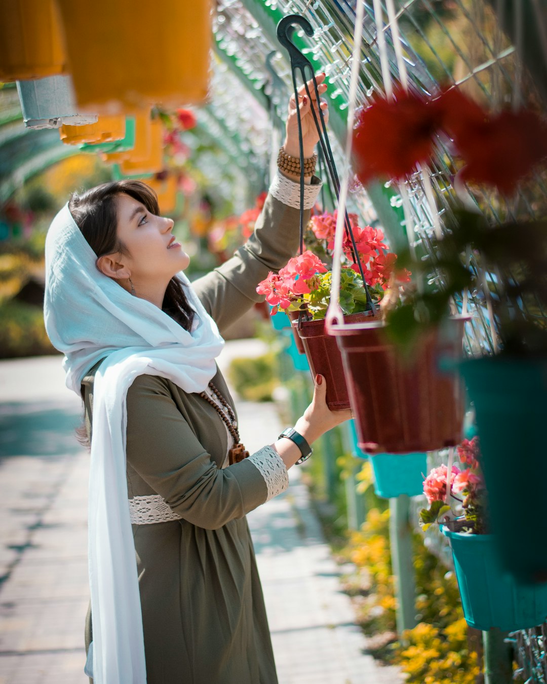 woman in white hijab holding red flower bouquet