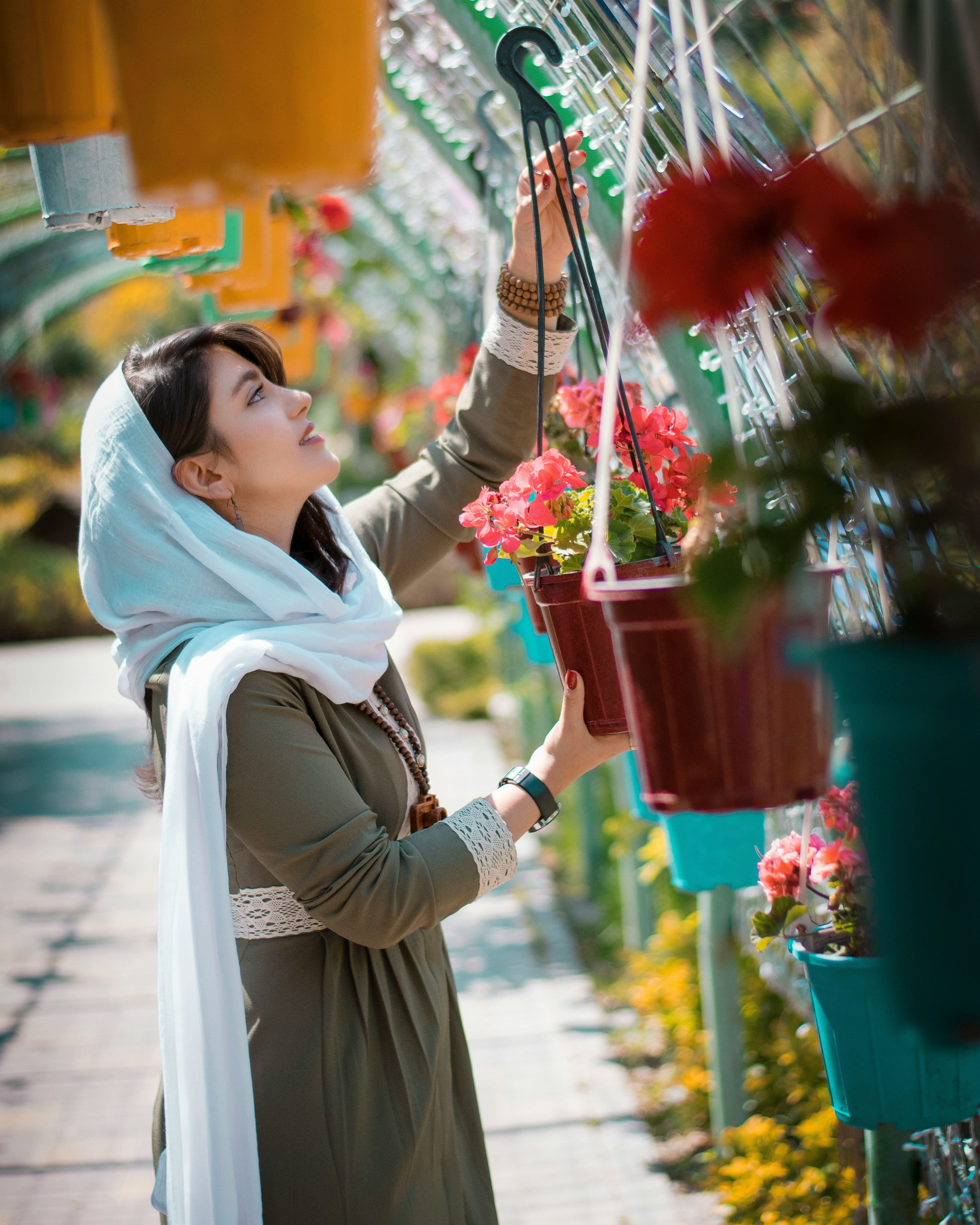 woman in white hijab holding red flower bouquet