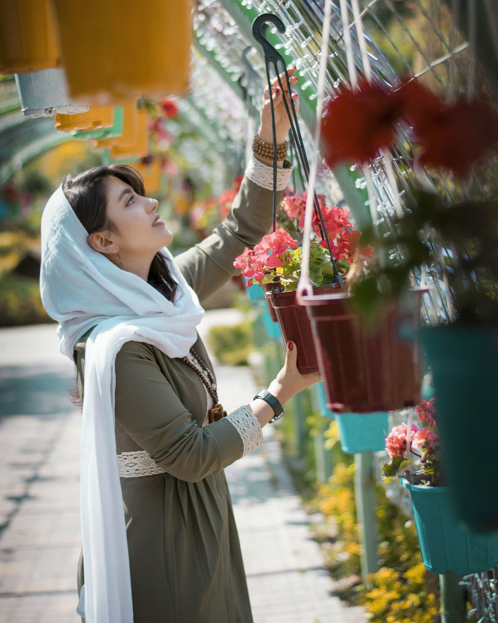 Femme en hijab blanc tenant un bouquet de fleurs rouges