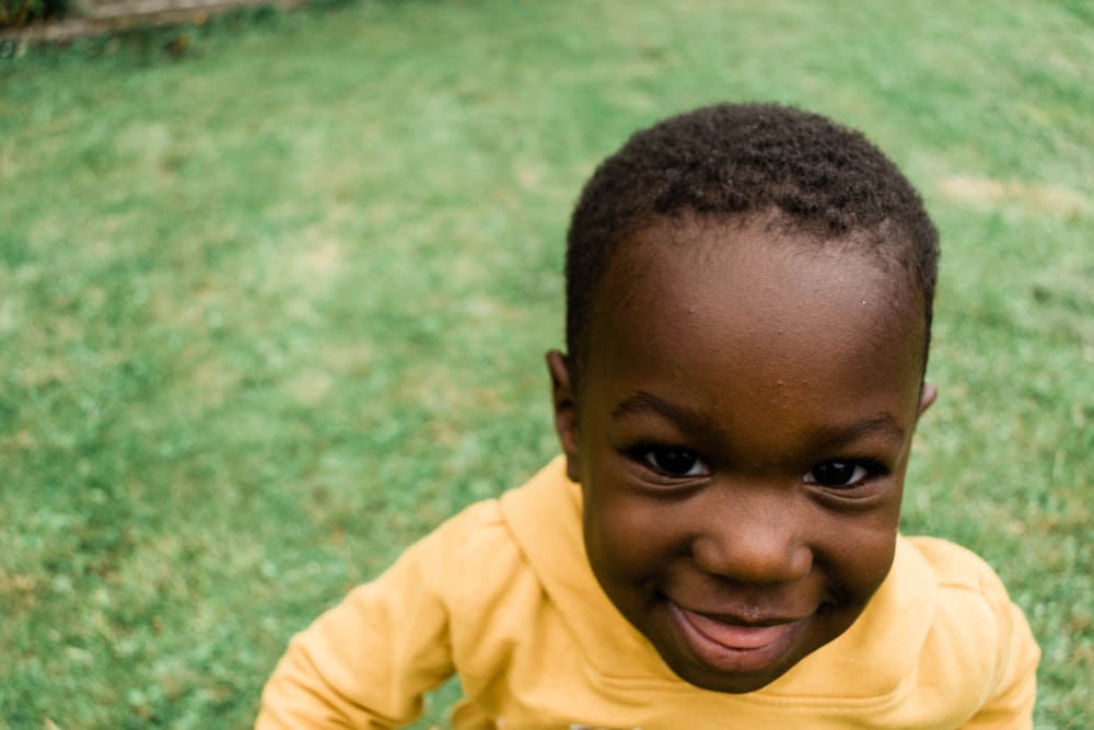 a young boy is smiling in the grass