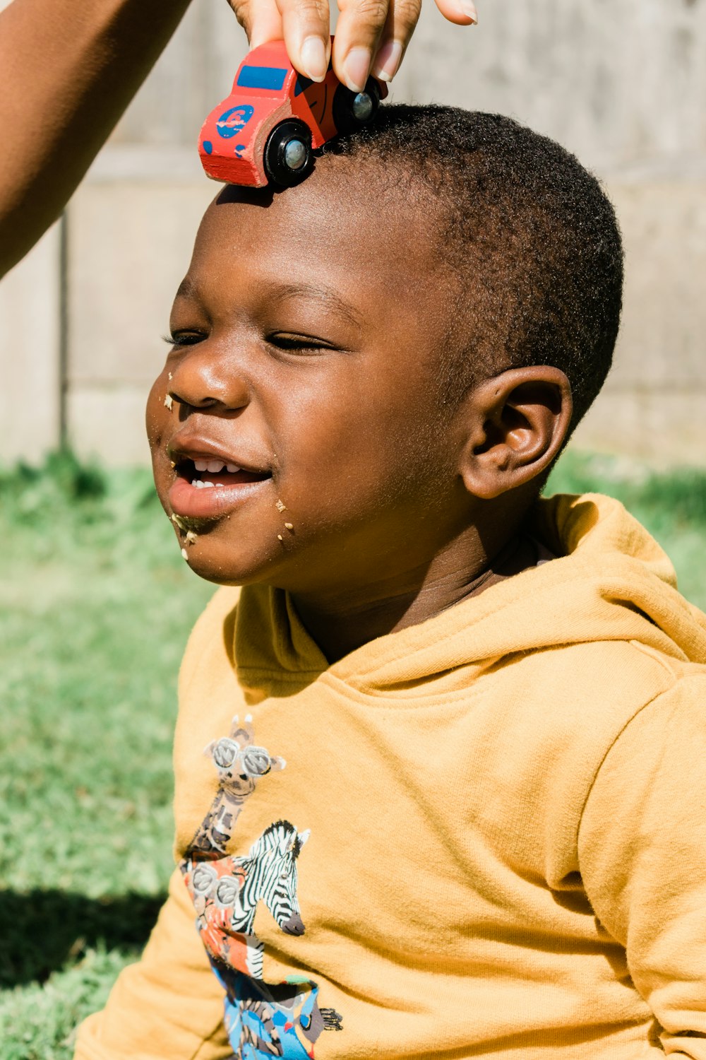 smiling boy in yellow hoodie wearing red and black sunglasses