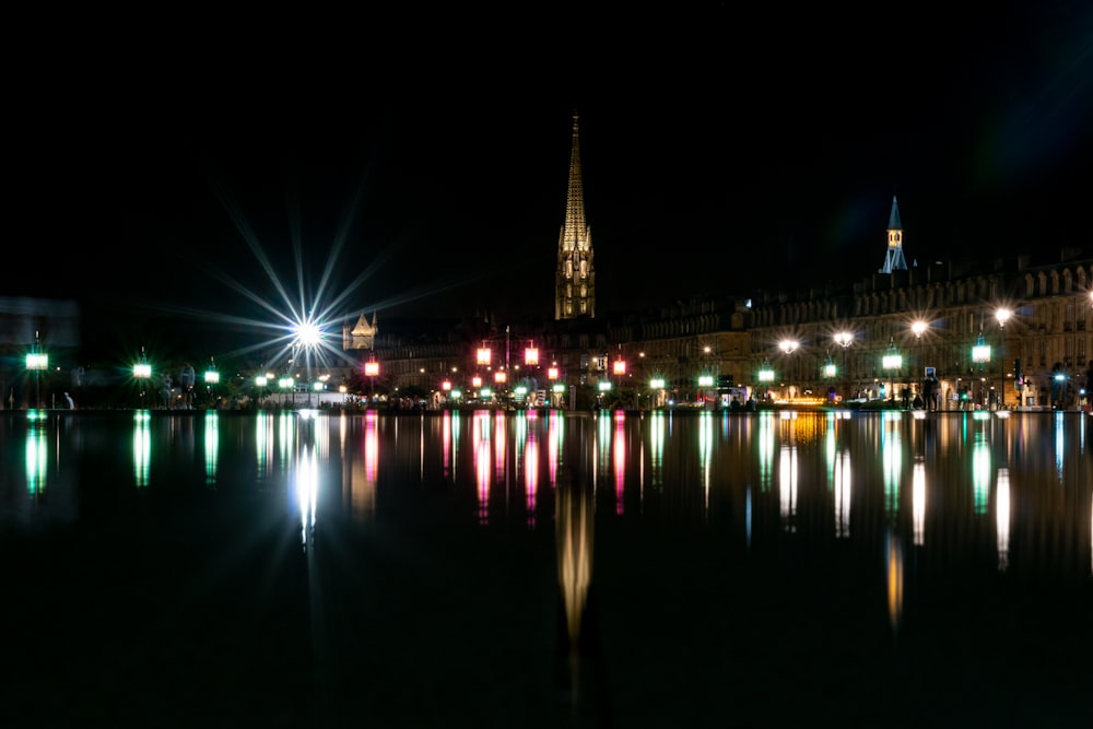 lighted city buildings near body of water during night time