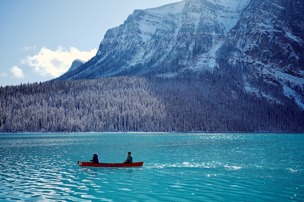 person riding on red kayak on lake during daytime