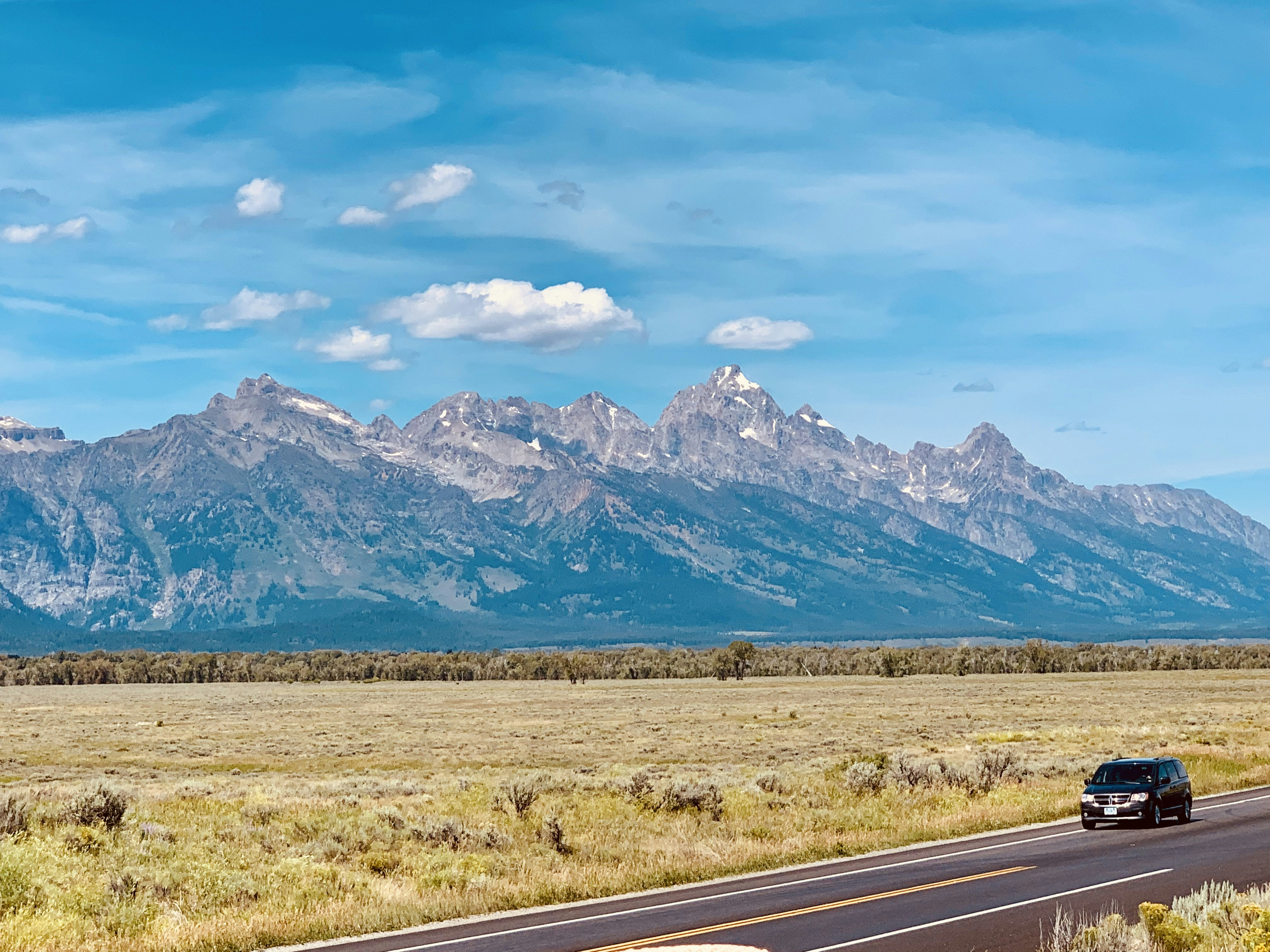 昼間の青空の下、山の近くの灰色のコンクリート道路