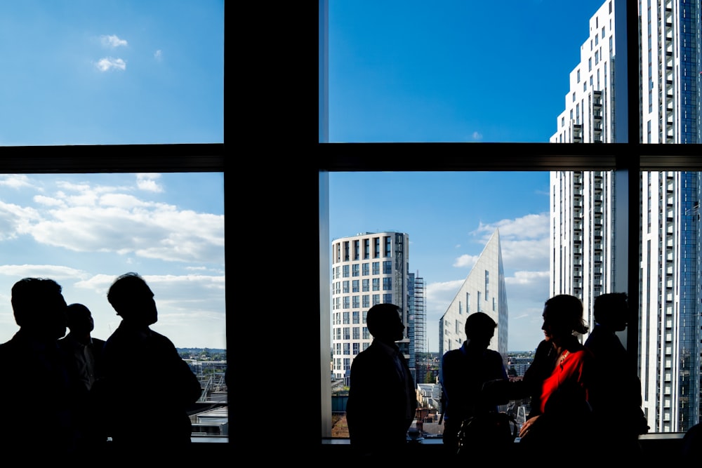 people standing on the window looking at the city during daytime