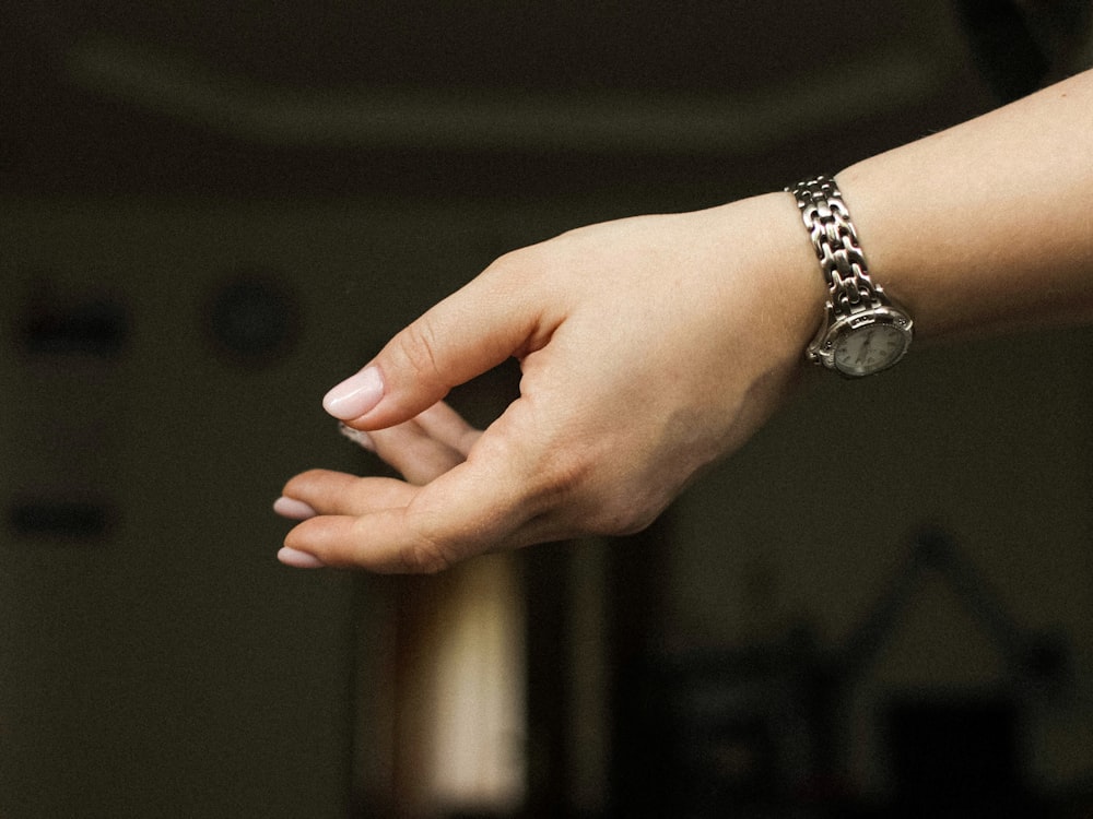 person wearing silver link bracelet watch