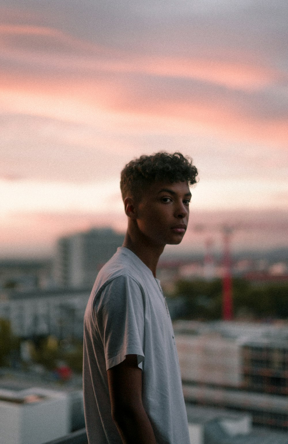 man in white crew neck shirt standing during sunset