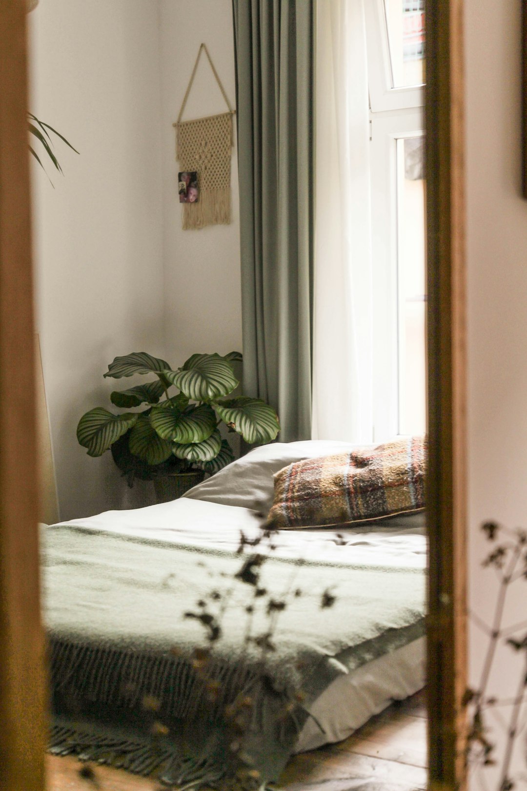 Bedroom with sheer curtains, plants and soft neutral bedding