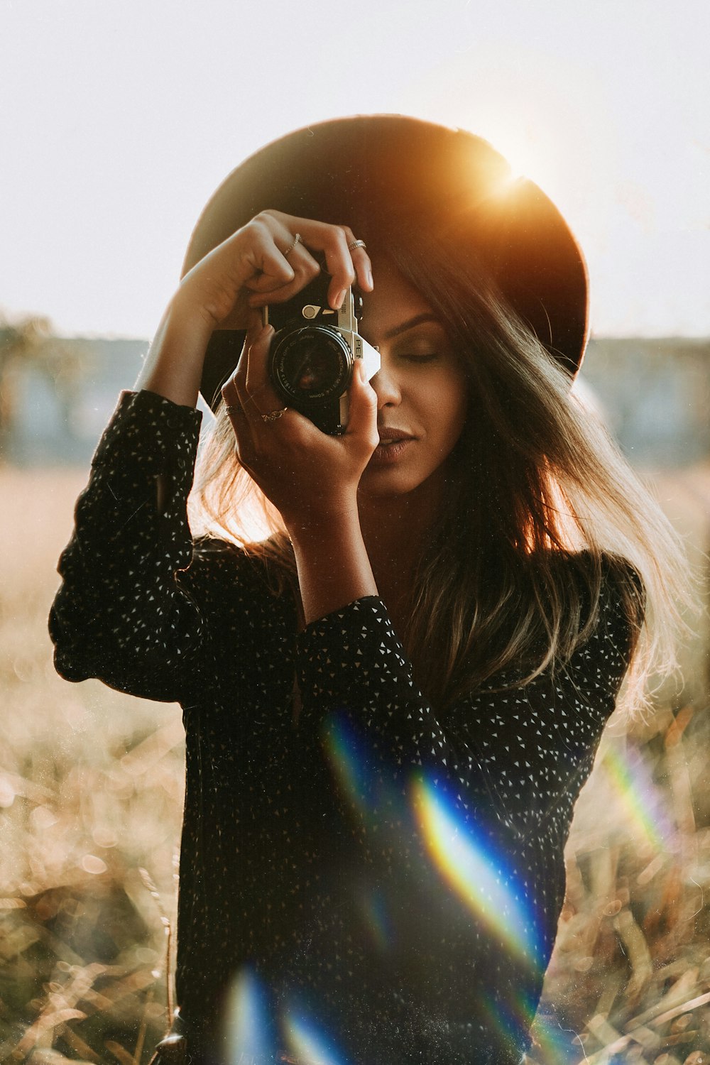 Femme en chemise noire à manches longues tenant un appareil photo reflex numérique noir