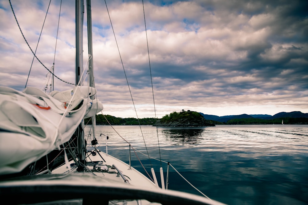 white sailboat on sea under gray clouds