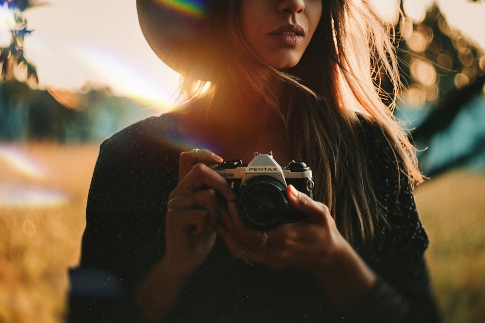 Femme tenant un appareil photo reflex numérique Nikon noir et argent