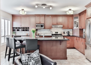 black leather padded chair beside brown wooden kitchen cabinet