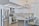 A modern kitchen featuring sleek white cabinetry and stainless steel appliances. The kitchen island has granite countertops with seating for three, set with placemats and glasses. A geometric light fixture hangs over the island, and subtle backsplash tiles add texture to the walls.