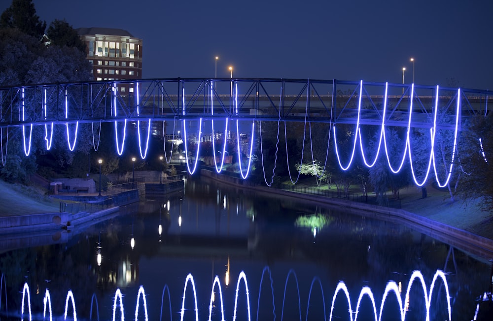 blue lighted bridge over river during night time
