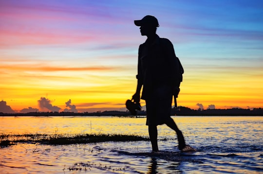 silhouette of man standing on water during sunset in Prey Veng Cambodia