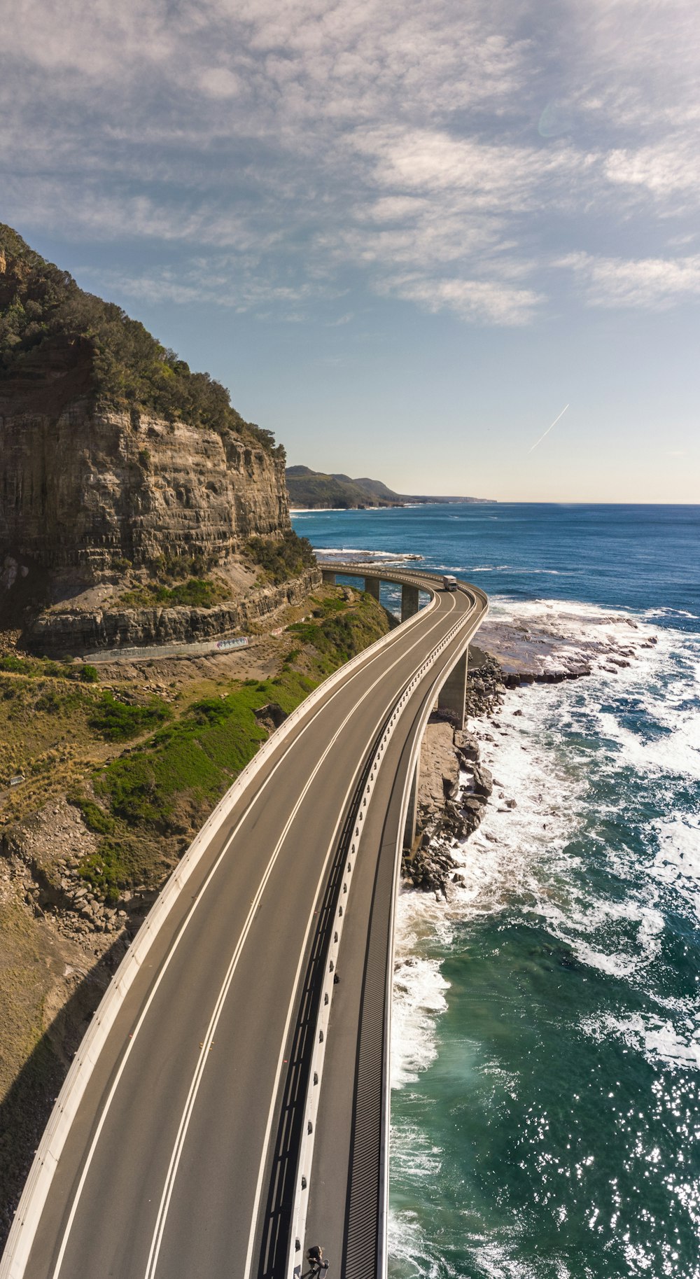 gray concrete road near body of water during daytime