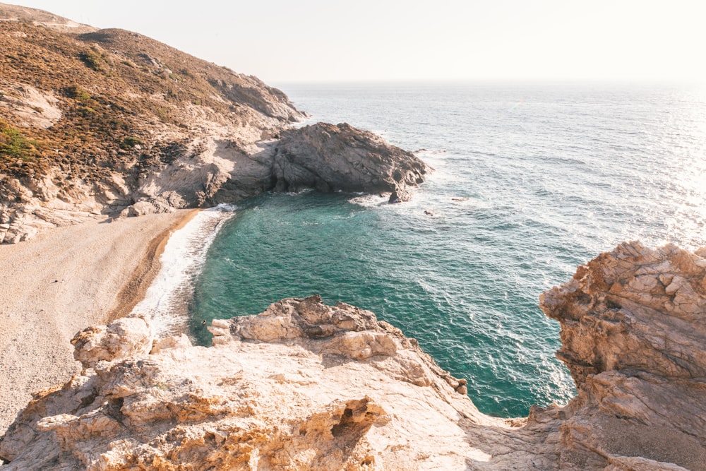 Montaña rocosa marrón junto al mar azul durante el día