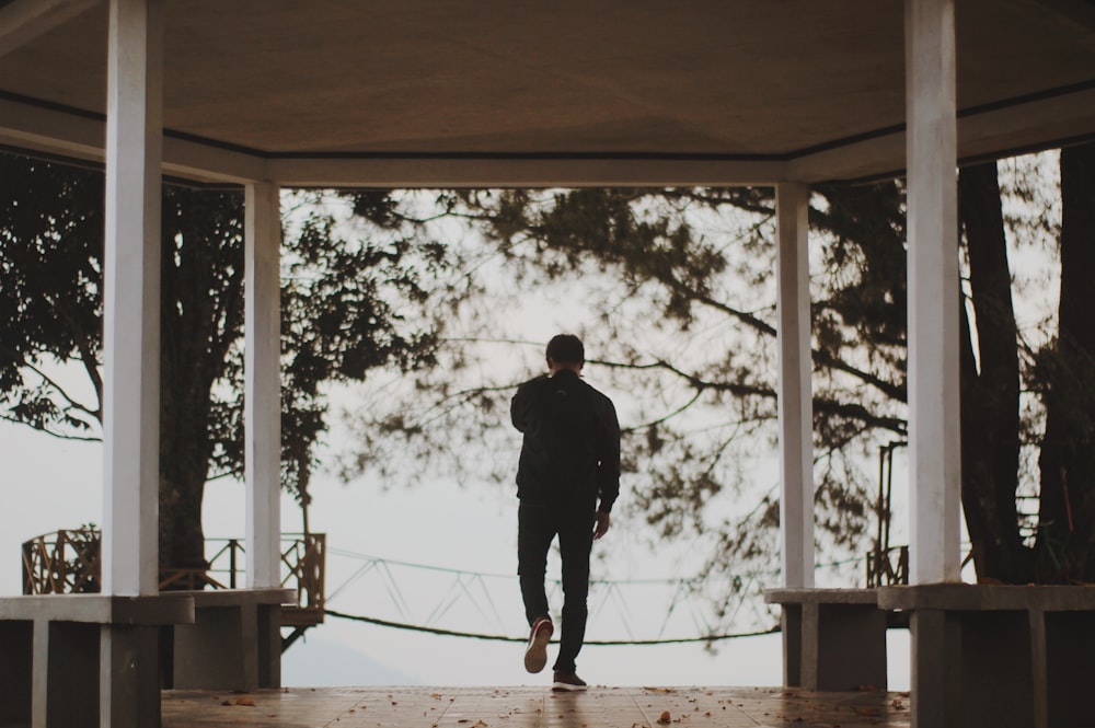 man in black jacket standing on brown wooden dock during daytime