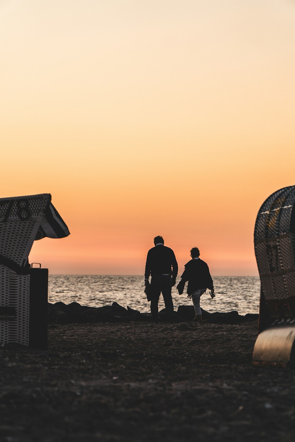 silhouette of people standing on beach during sunset