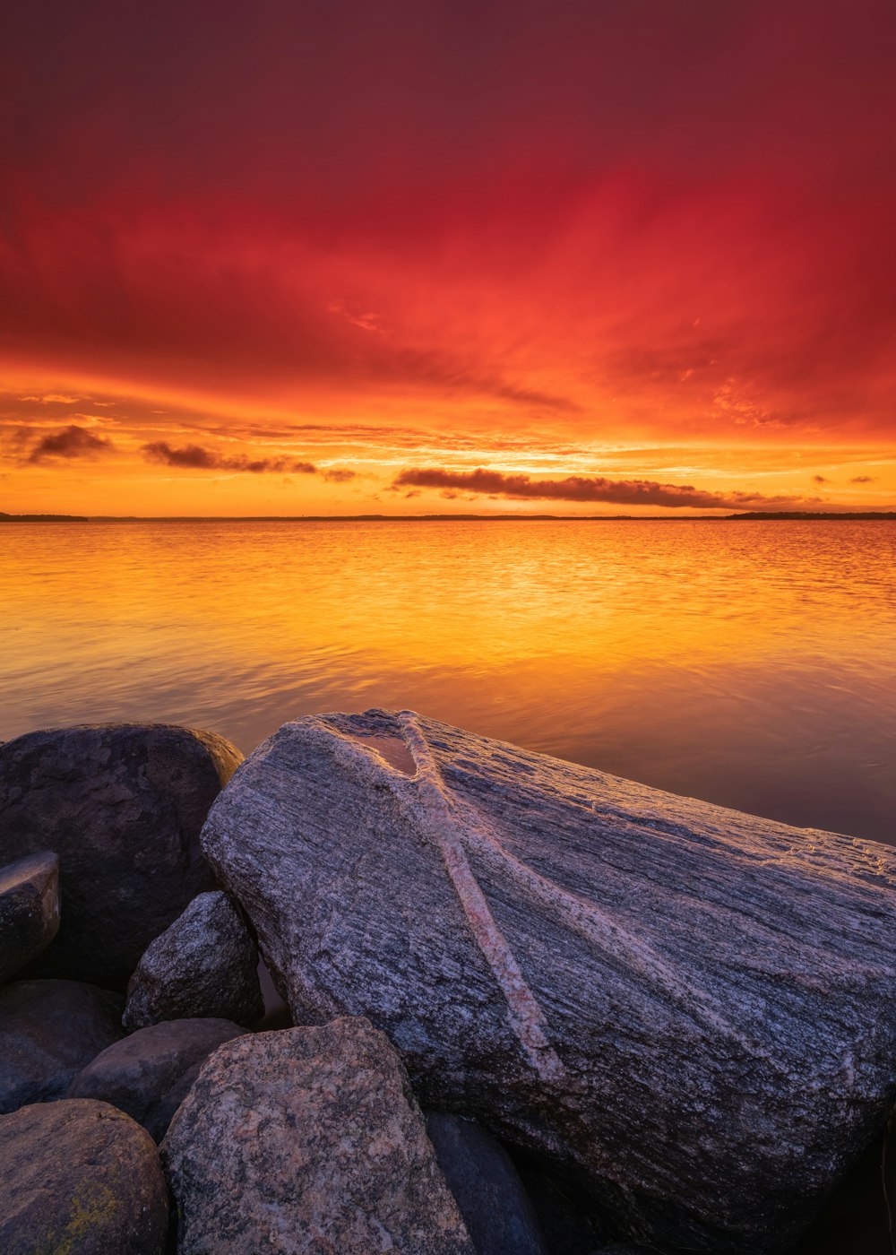 gray and black rocks beside body of water during sunset