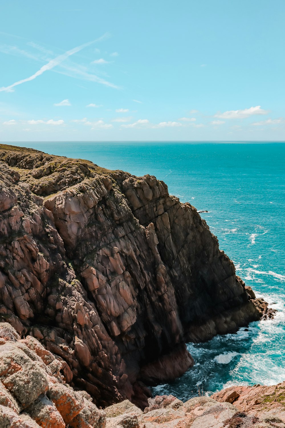 brown rocky mountain beside blue sea under blue sky during daytime