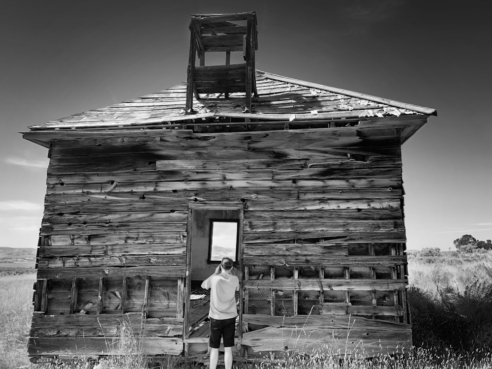 woman in white shirt and black pants standing on wooden house