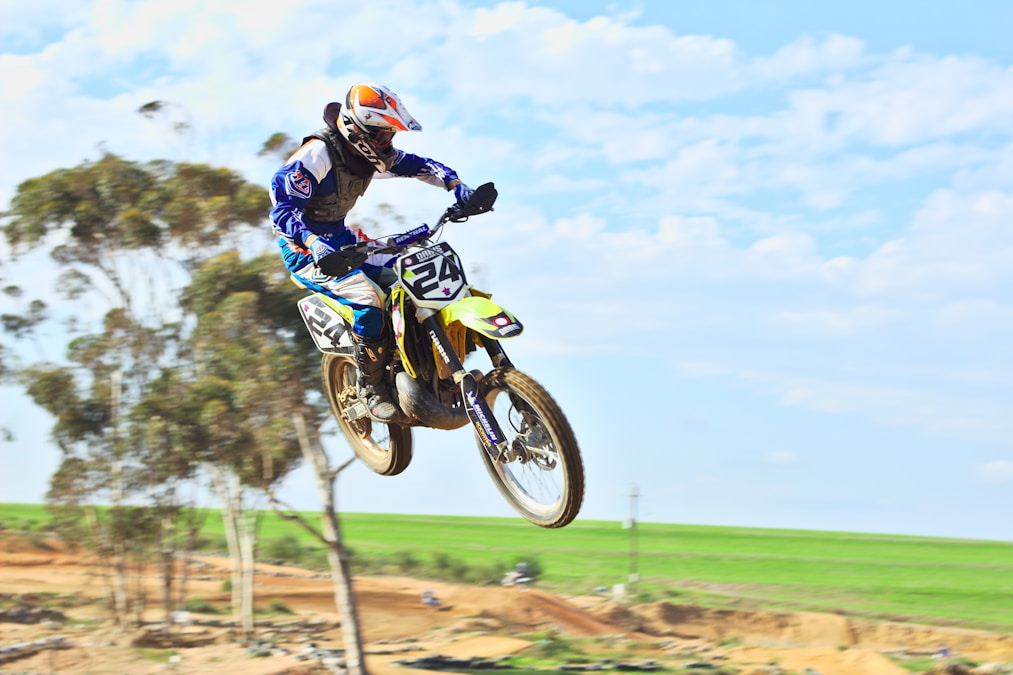 Motocross rider jumping a dirt bike while wearing a black chest protector over the jersey