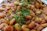 Close-up of a vibrant, spicy shrimp dish garnished with fresh herbs on a rustic plate.